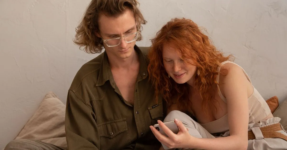 Two people sitting close, looking at a phone together