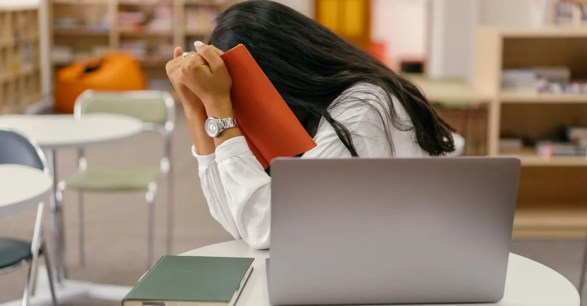 Person watching a screen from behind a laptop