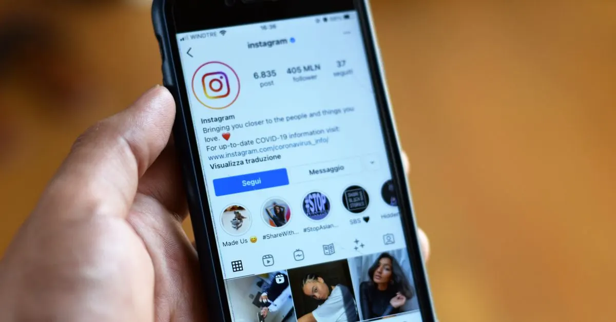 A hand holding a smartphone open on an Instagram profile with Story Highlights