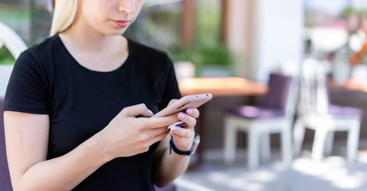 Young woman checking Instagram on her phone at a cafe