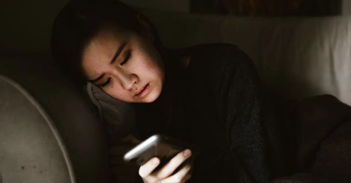 Woman lying in the dark checking her phone late at night